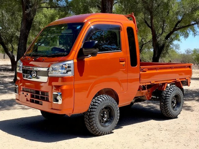 Daihatsu Hijet Jumbo orange model on sand under trees